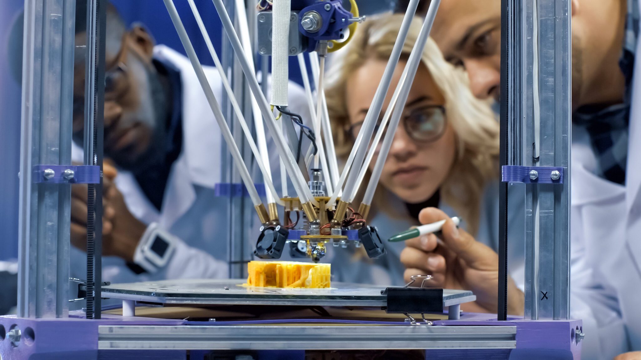 Researchers watching 3-D printing machine in process