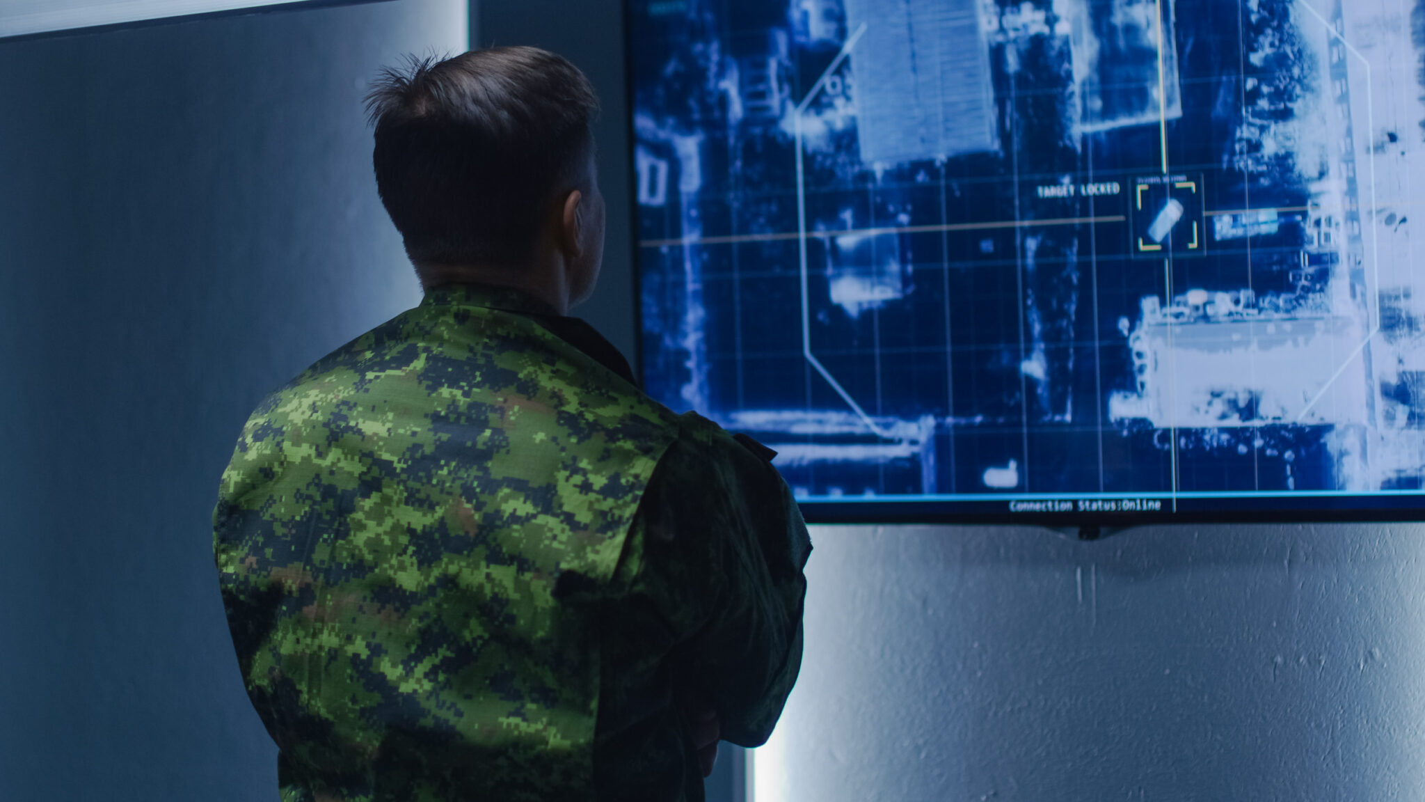Military Man / Army Officer Watches Satellite Surveillance Footage / Car Tracking of the Target on Wall TV Screen. Secret Military Spying Operation in the Surveillance Center / System Control Room.