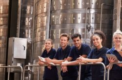 Staff at a wine factory smiling to camera from a gangway