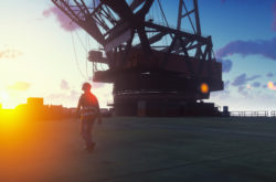 Oil worker walks on an oil platform at sunrise.