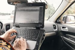 A police officer seated inside a patrol vehicle, equipped with a TOUGHBOOK device, diligently carrying out law enforcement duties. The rugged and reliable technology enables officers to stay connected, access critical information, and collaborate effectively while on the field.