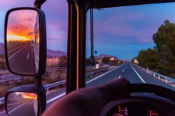View of the highway from the driving position of a truck, with a dramatic sky sunset.